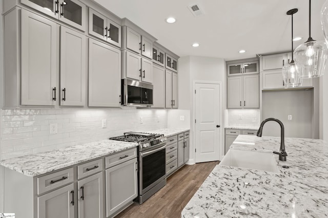 kitchen with visible vents, gray cabinets, a sink, dark wood-type flooring, and appliances with stainless steel finishes