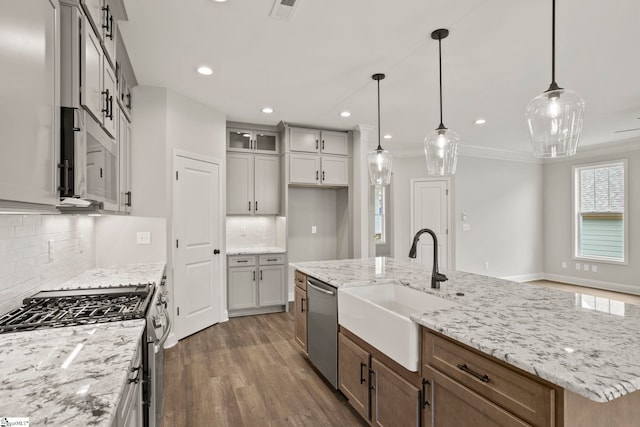kitchen featuring light stone counters, decorative backsplash, an island with sink, stainless steel appliances, and dark wood-style floors