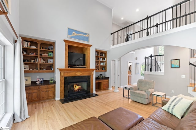 361 E Killarney Lk, Moore, SC 29369 - living room with a high ceiling, arched walkways, light wood-type flooring, a fireplace, and stairs