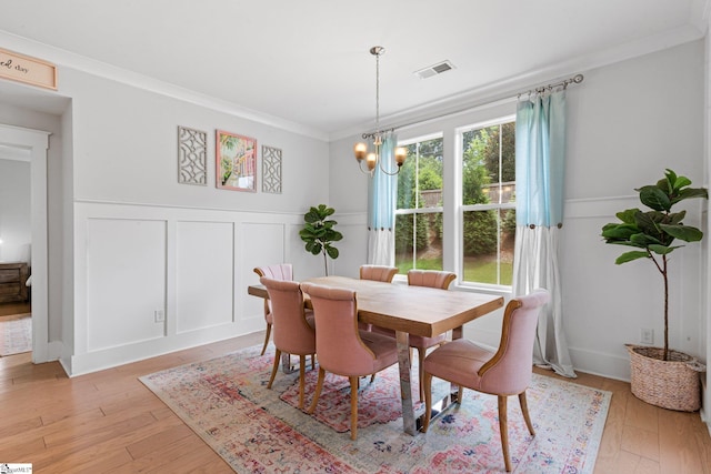 309 Nebbiolo Ln, Simpsonville, SC 29681 - dining room with a decorative wall, a chandelier, crown molding, wainscoting, and light wood-type flooring