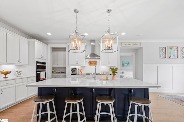 309 Nebbiolo Ln, Simpsonville, SC 29681 - kitchen with wall chimney exhaust hood, stainless steel double oven, a chandelier, a breakfast bar area, and white cabinets