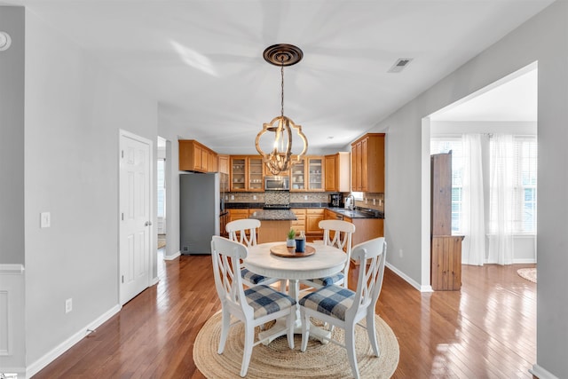 dining space featuring baseboards, visible vents, an inviting chandelier, and wood-type flooring
