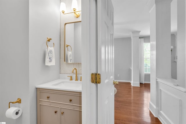 bathroom featuring backsplash, baseboards, wood finished floors, and vanity