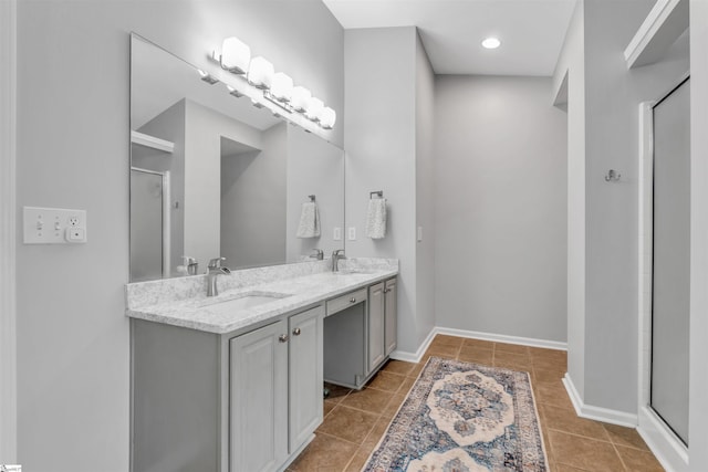 full bath with double vanity, tile patterned flooring, a stall shower, and a sink