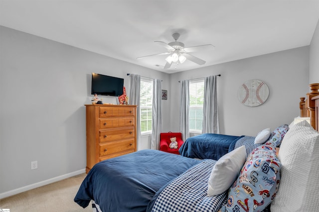 bedroom with a ceiling fan, baseboards, and light carpet