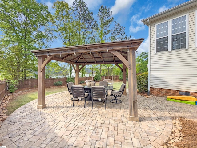 view of patio with a fenced backyard, a gazebo, and outdoor dining area