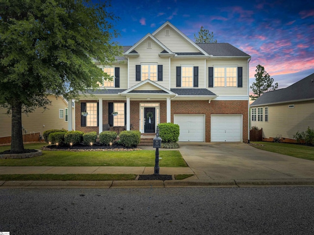 view of front facade featuring brick siding, an attached garage, a front lawn, and driveway