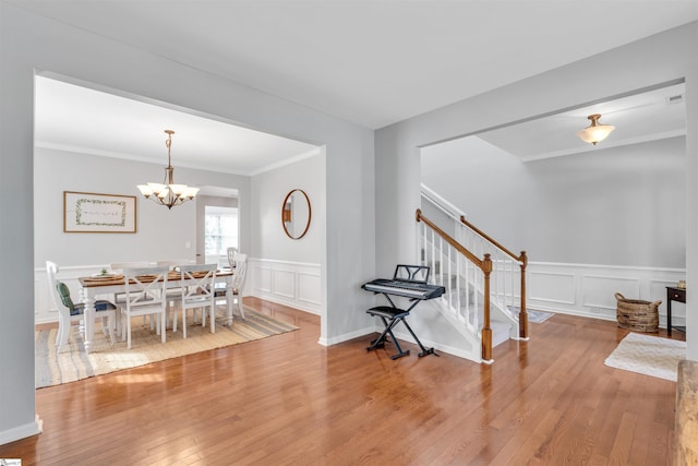 dining space with wood finished floors, a notable chandelier, stairway, and a decorative wall