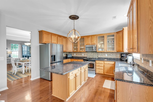 kitchen featuring stainless steel appliances, light wood-style flooring, a sink, and a notable chandelier