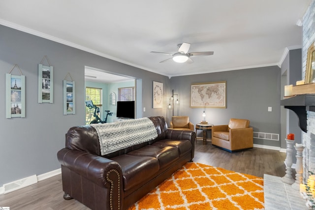 living room featuring baseboards, visible vents, a fireplace, and crown molding