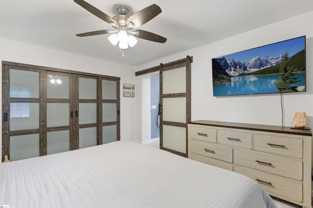 bedroom featuring a ceiling fan, baseboards, and a barn door