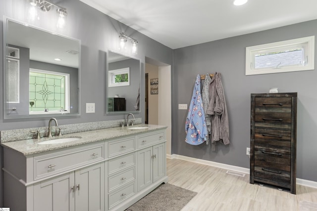 bathroom featuring visible vents, baseboards, a sink, and double vanity