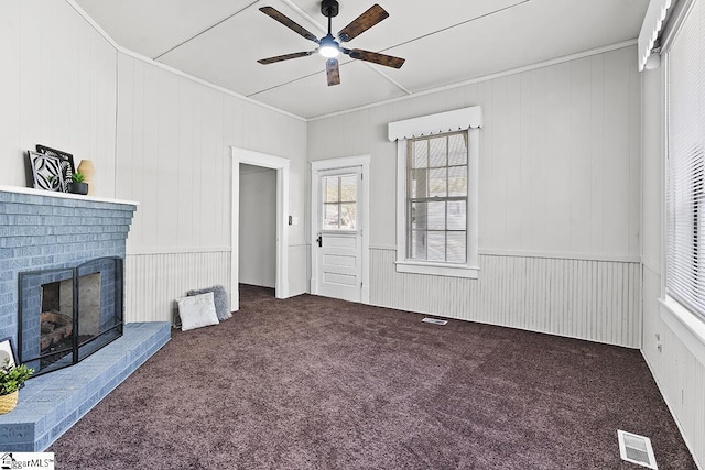 unfurnished living room with carpet, visible vents, a ceiling fan, ornamental molding, and a fireplace