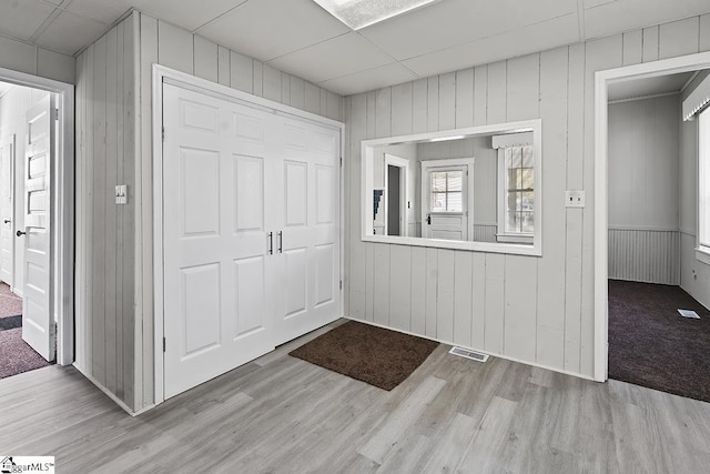 entryway with wood walls, wood finished floors, and visible vents