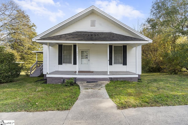 view of front of house with a front lawn, roof with shingles, and a porch