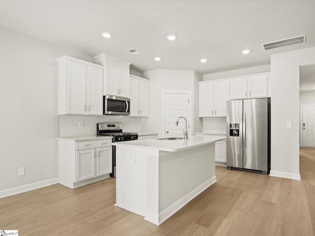 225 Maxwell Dr, Easley, SC 29642 - kitchen featuring appliances with stainless steel finishes, a sink, light wood-style floors, tasteful backsplash, and white cabinets