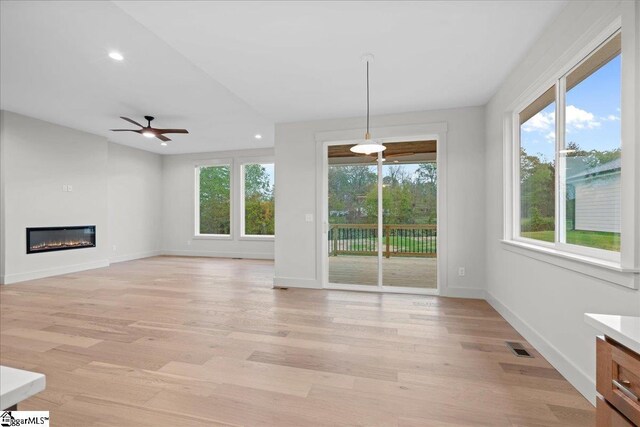 204 Tot Howell Rd, Greer, SC 29651 - unfurnished living room with a glass covered fireplace, light wood-style floors, a wealth of natural light, and a ceiling fan