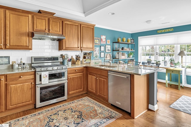 kitchen featuring a sink, brown cabinetry, under cabinet range hood, appliances with stainless steel finishes, and ornamental molding