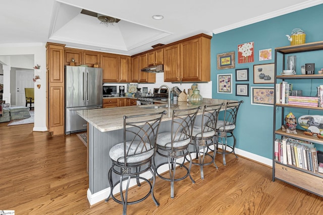 kitchen featuring ornamental molding, a peninsula, appliances with stainless steel finishes, and a sink