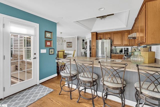 kitchen with a peninsula, baseboards, freestanding refrigerator, an inviting chandelier, and brown cabinets