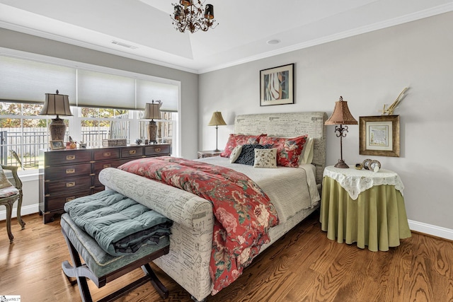 bedroom featuring baseboards, visible vents, a notable chandelier, wood finished floors, and ornamental molding