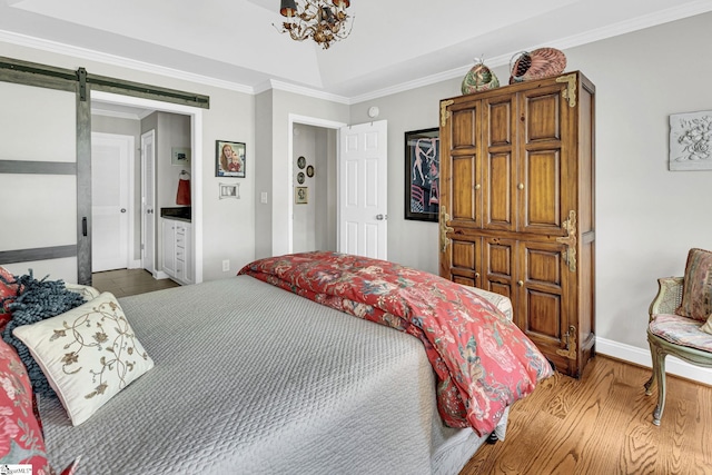bedroom featuring a barn door, wood finished floors, ornamental molding, baseboards, and a chandelier