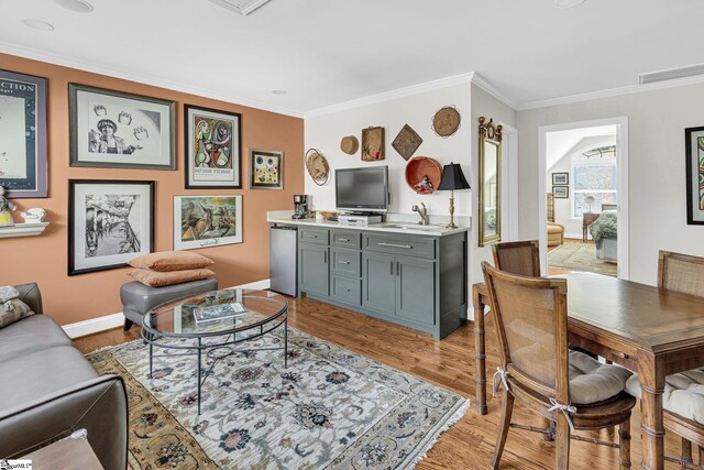 living room with visible vents, light wood-style flooring, baseboards, and ornamental molding
