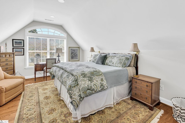 bedroom with lofted ceiling, baseboards, wood finished floors, and visible vents