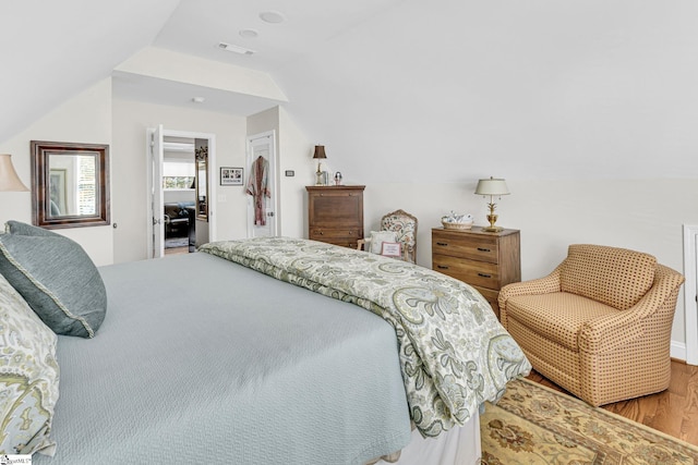 bedroom with lofted ceiling, wood finished floors, and visible vents