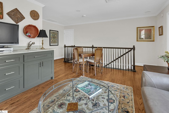 living room featuring wood finished floors, visible vents, crown molding, and baseboards