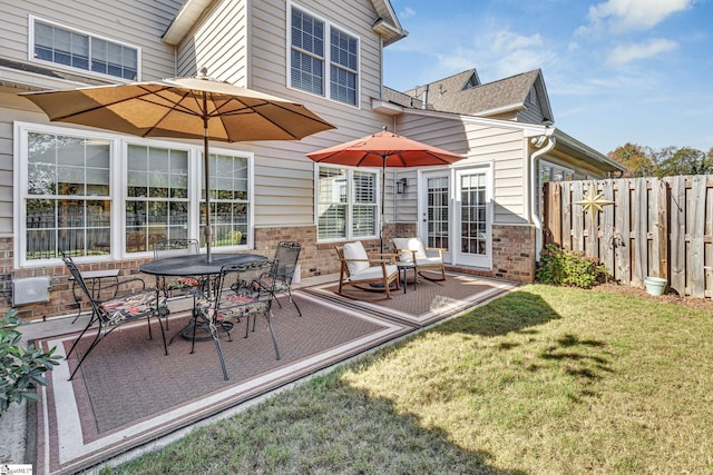 back of house featuring fence, a yard, outdoor dining area, a patio, and brick siding