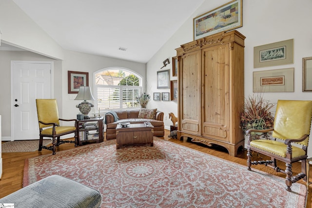 living area with baseboards, wood finished floors, and high vaulted ceiling