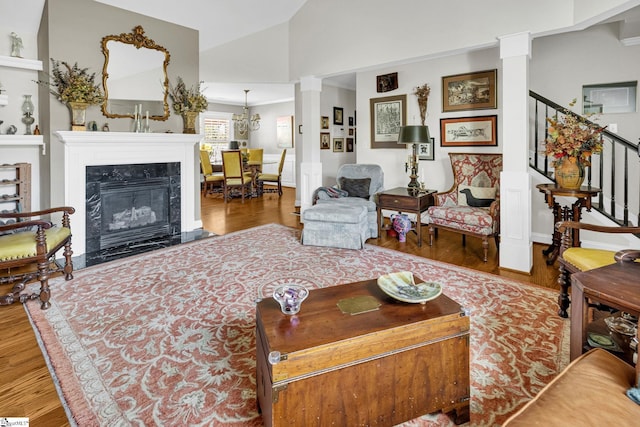 living area featuring lofted ceiling, decorative columns, and wood finished floors