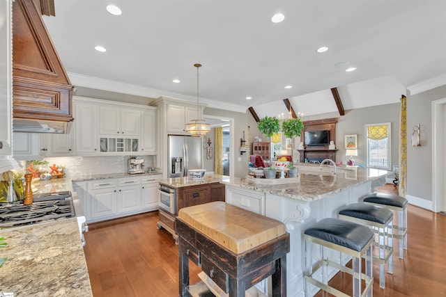 kitchen featuring dark wood finished floors, stainless steel fridge, a large island with sink, and decorative backsplash