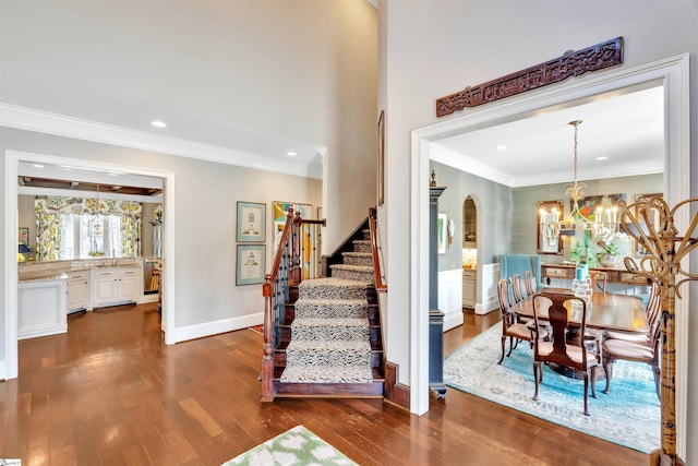 stairs featuring arched walkways, an inviting chandelier, recessed lighting, wood finished floors, and ornamental molding