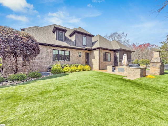 back of house featuring exterior kitchen, a yard, brick siding, and a shingled roof