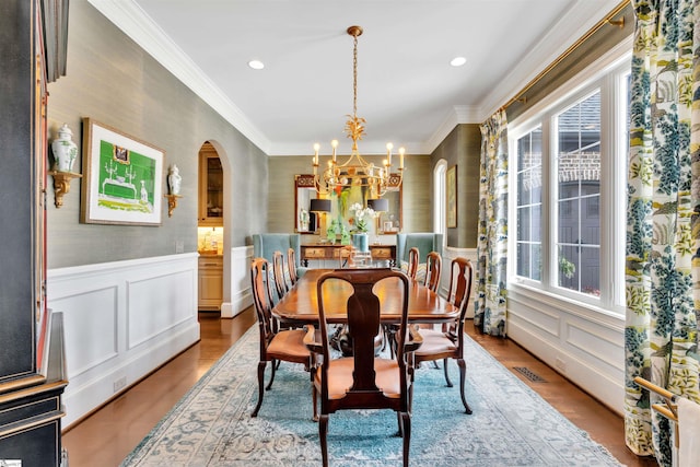 dining room with a chandelier, arched walkways, visible vents, and a wainscoted wall