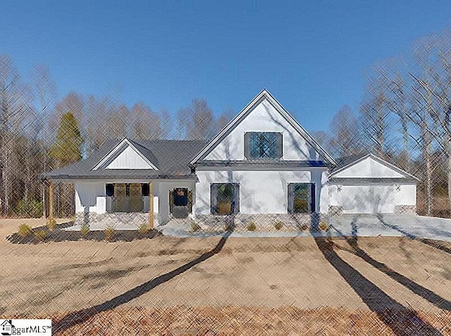 view of front facade with stucco siding, a detached garage, and covered porch
