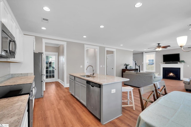 200 Noble St, Greer, SC 29651 - kitchen featuring a ceiling fan, a kitchen breakfast bar, a sink, a warm lit fireplace, and stainless steel appliances