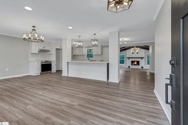 181 Skyland Dr, Clinton, SC 29325 - unfurnished living room featuring baseboards, a notable chandelier, wood finished floors, a warm lit fireplace, and crown molding