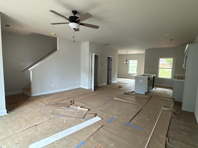 unfurnished living room featuring stairs and ceiling fan