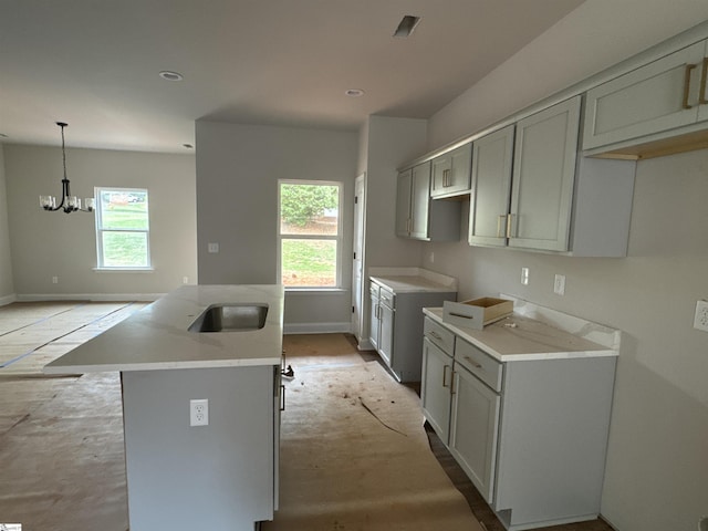 kitchen with plenty of natural light, a kitchen island with sink, and gray cabinets