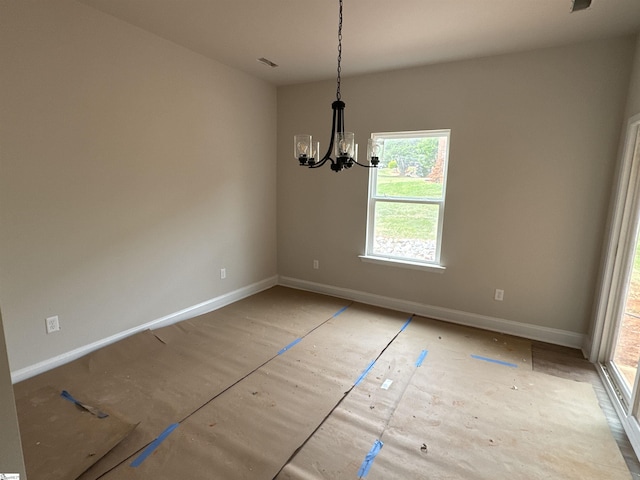 unfurnished dining area with a chandelier, a wealth of natural light, and baseboards