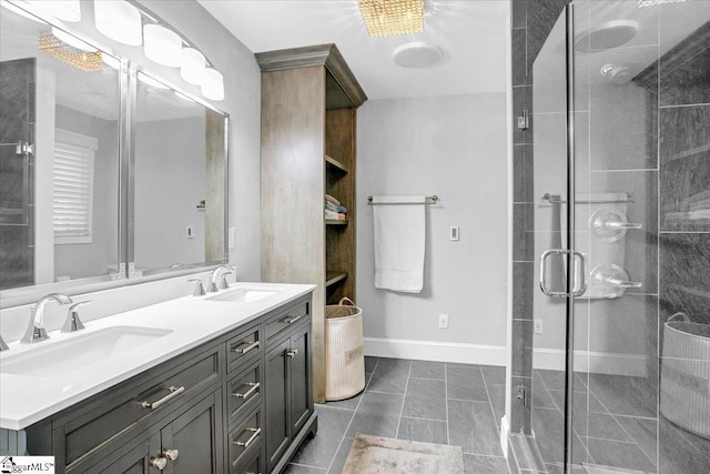 bathroom with double vanity, a shower stall, baseboards, and a sink