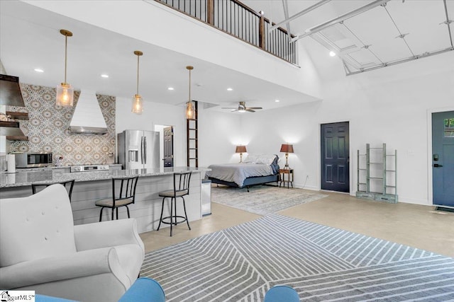 bedroom with stainless steel refrigerator with ice dispenser, baseboards, a towering ceiling, and concrete floors
