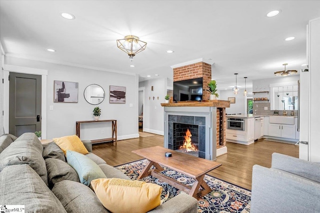 living room featuring light wood finished floors, a tiled fireplace, and recessed lighting