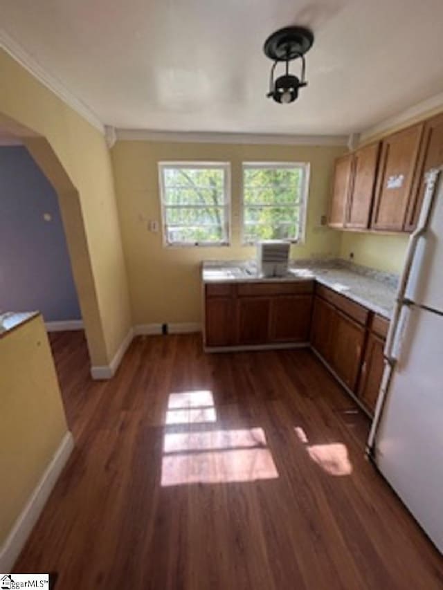 kitchen featuring dark wood finished floors, baseboards, freestanding refrigerator, light countertops, and ornamental molding