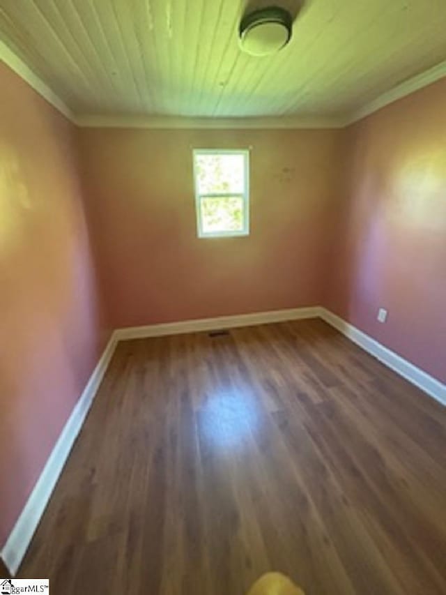 unfurnished room featuring wood finished floors, wood ceiling, baseboards, and ornamental molding