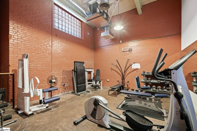 gym featuring brick wall and a high ceiling