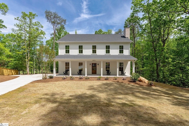view of front of house featuring a porch, a chimney, roof with shingles, and concrete driveway